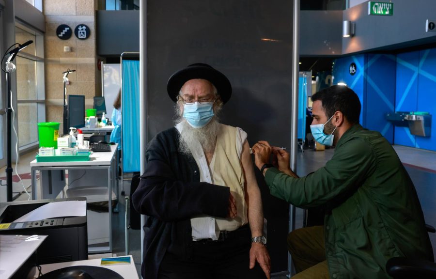 A+healthcare+worker+administers+a+COVID-19+vaccine+to+an+ultra-Orthodox+Jewish+man+at+Israels+Clalit+Health+Services+in+Jerusalem%2C+on+January+6%2C+2021.+%28Photo+by+MENAHEM+KAHANA+%2F+AFP%29+%28Photo+by+MENAHEM+KAHANA%2FAFP+via+Getty+Images%29