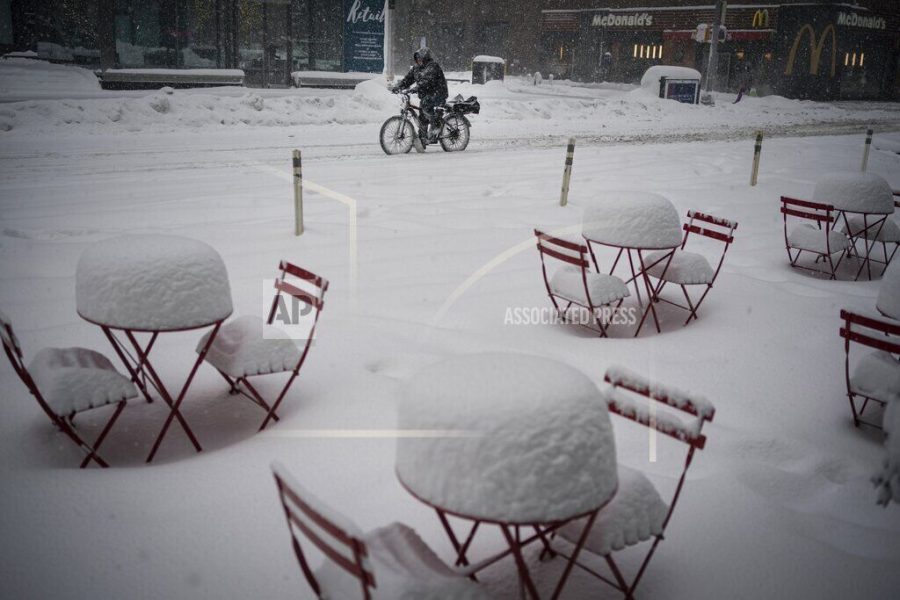 A man delivers food on his electric bicycle as he rides past snow-covered dining tables in midtown during a snowstorm, Monday, Feb. 1, 2021, in New York. (AP Photo/Wong Maye-E)