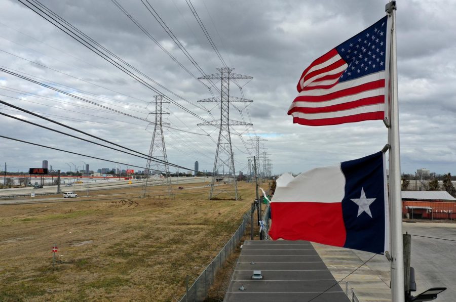 The+U.S.+and+Texas+flags+fly+in+front+of+high+voltage+transmission+towers+on+February+21%2C+2021+in+Houston%2C+Texas.+Millions+of+Texans+lost+power+when+winter+storm+Uri+hit+the+state+and+knocked+out+coal%2C+natural+gas+and+nuclear+plants+that+were+unprepared+for+the+freezing+temperatures+brought+on+by+the+storm.%C2%A0