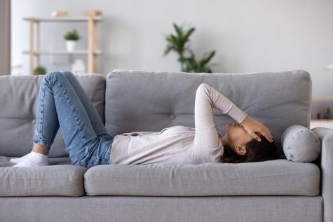 Full length young woman lying on sofa suffers from heartache cover face with hands crying feels desperate unhappy unwell having mental pain or serious health problems, beak up divorce abortion concept