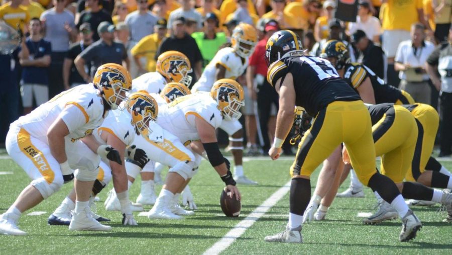 Kent State center Sam Allan (54) prepares to snap the ball while facing down Iowas defensive line. The Flashes would give up 7 sacks for 39 yards and a safety.