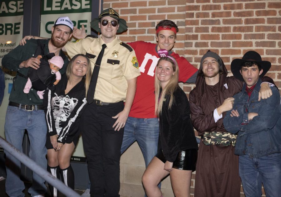 Students pose in their costumes for a picture while waiting in line to get into Barflyy Retro Bar And Arcade, a popular bar in downtown Kent, on Sunday Oct. 31, 2021.