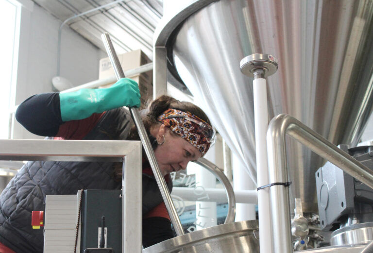 Jennifer Hermann cleans out a Lauter tun, a large tank used in the brewing process to separate the mash (grain mixture) into wort, which can then be fermented using yeast.