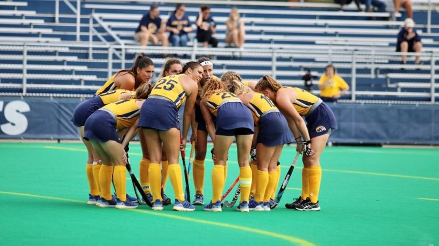 Members of the Kent State field hockey team huddle up during a match. 