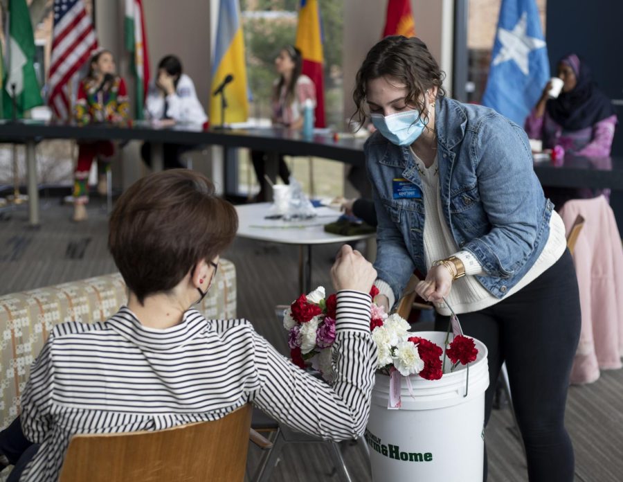Graduate assistant, Olivia Grahman, hands out carnation flowers to women attending the International Womens Day event inside the Center for Undergraduate Excellence on Mar. 8, 2022. 
