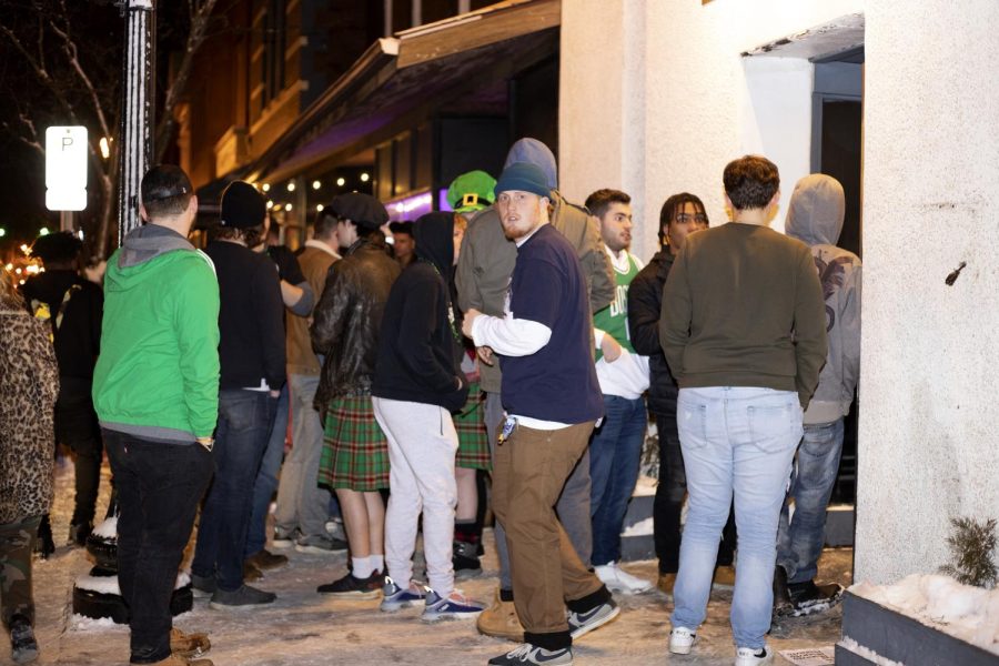 A line of students and community members stand outside 157 Lounge on Fake Paddys Day. 