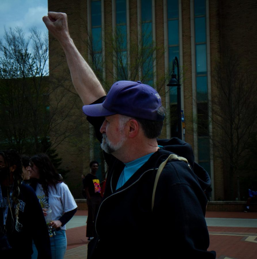 As the students start marching toward the rock, a man named Dennis Rein holds his fist in the air as an act of solidarity toward the marchers at the protest for pro-choice rights on Thursday, May 5. Dennis is a May 4 survivor who was visiting for the May 4 celebrations the day before when he saw the protest happening on the K.