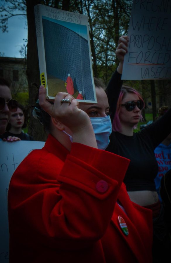 A student dressed in a red coat holds The Handmaids tale during the protest for pro-choice rights on Thursday, May 5.