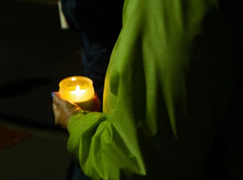 A woman in a bright green jacket held her own candle for the May 4 candlelight vigil on the morning of Wednesday, May 4.