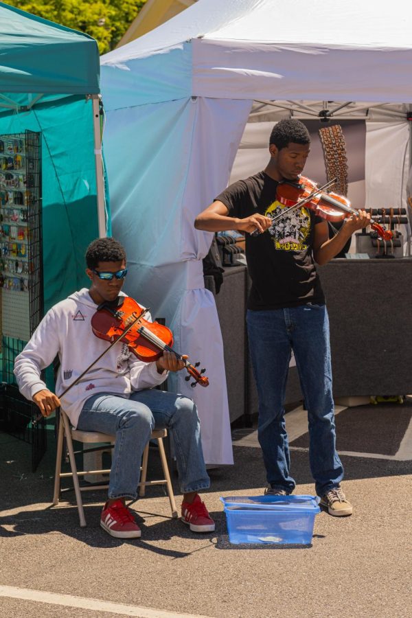 Street Musicians playing violin for onlookers during the Art and Wine Festival on June 4, 2022. Attendees enjoyed modern songs played on classical instruments as they shopped.