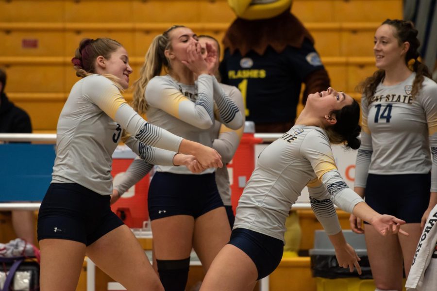 Kent State volleyball team members on the sideline celebrate winning a rally. 