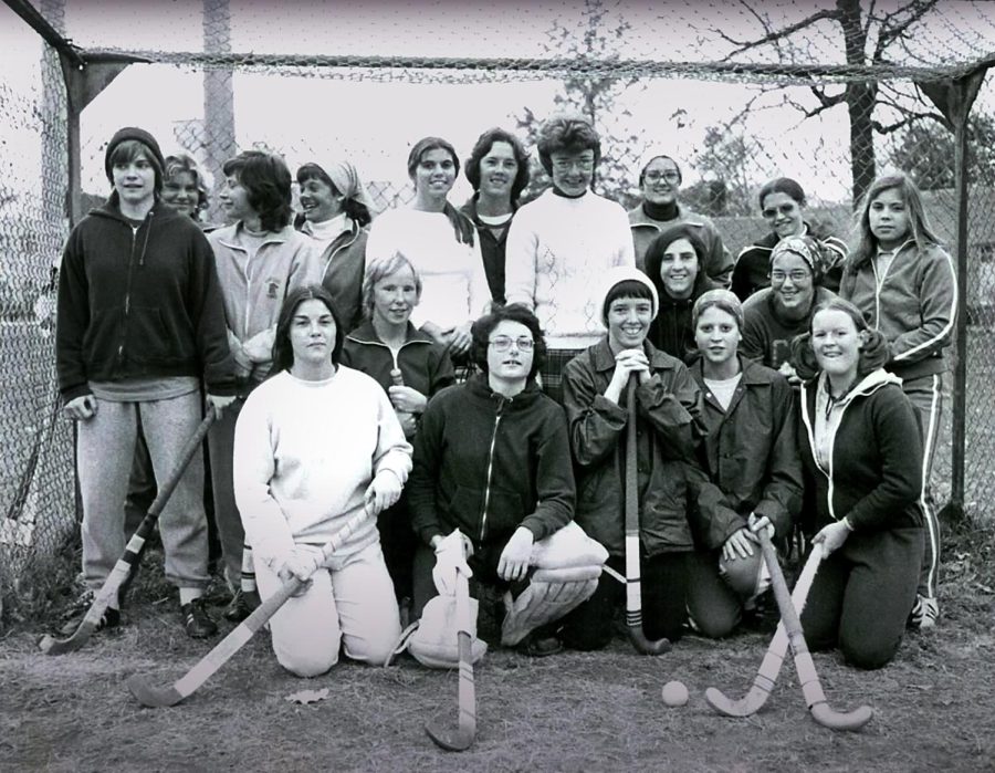 Kent States 1975 field hockey team poses with Coach Judy Devine, center back, in front of a homemade goal cage. Each athlete is wearing her own practice gear and holding hockey sticks that were borrowed from the physical education inventory. 
