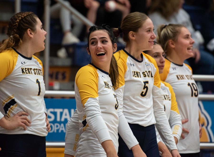 The Kent State volleyball team members on the sideline celebrate after winning a rally. 