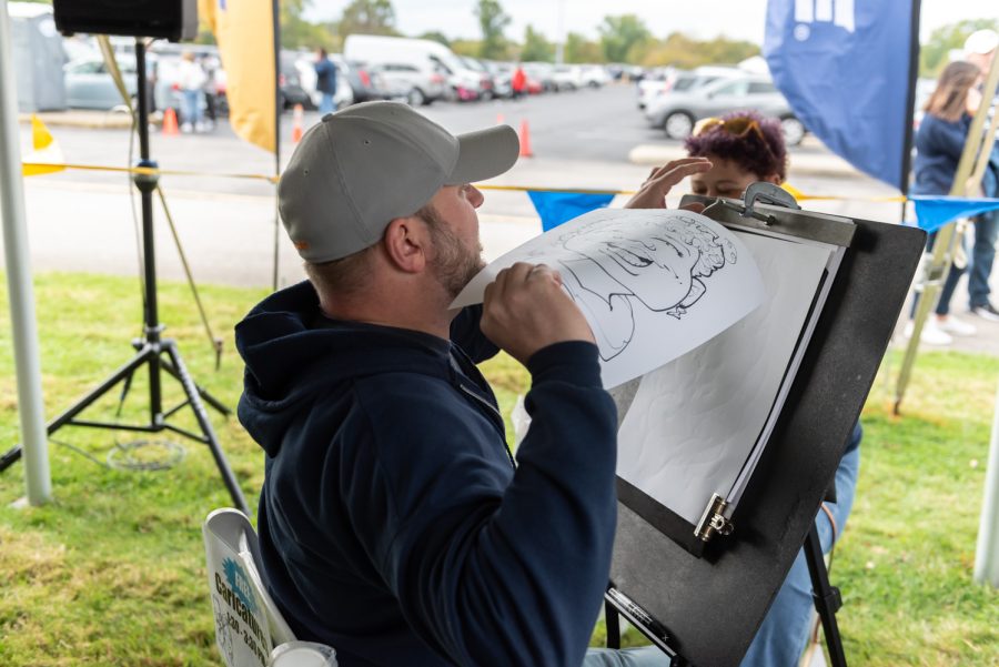 Jamie Rockwell, a caricature artist, finishes up his drawing of an attendee and shows it to her.