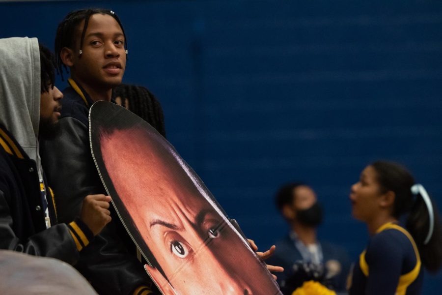 Armed with a giant cut-out of The Rocks face, Kent State senior Quintin Cooks cheers on KSUs mens basketball team.