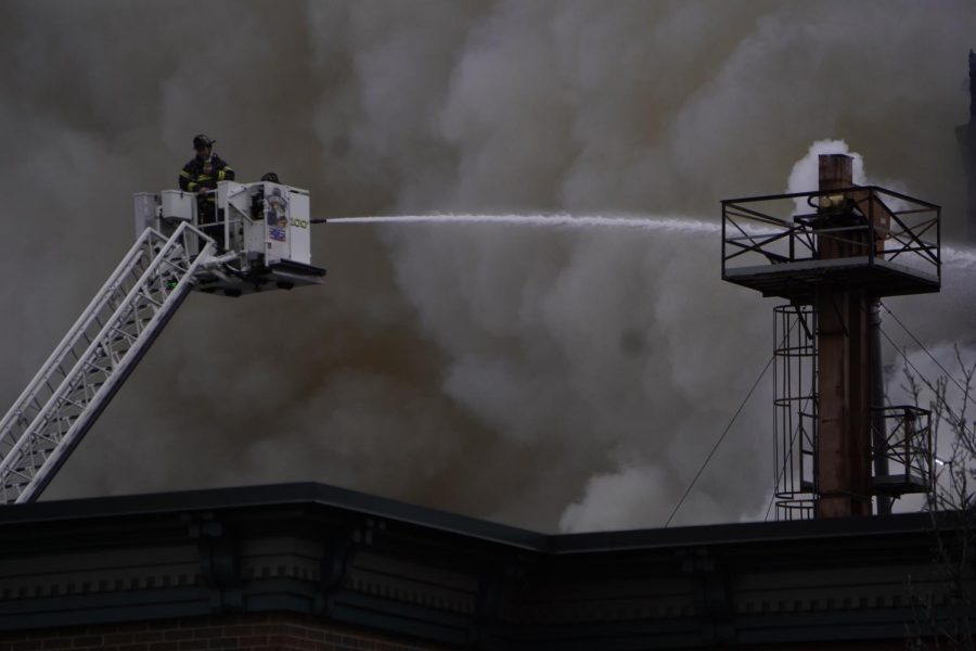 A firefighter aims the hose toward the mass of smoke.
