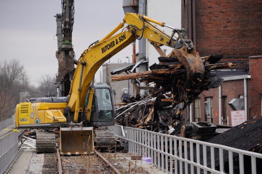 Moving down the train tracks, the backhoe operator moves the debris to a separate pile.