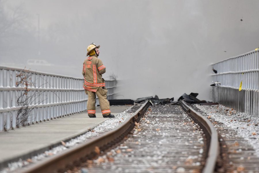 A firefighter watches from the track adjacent to the Star of the West Mill as debris knocked from the building piles up on the rails.