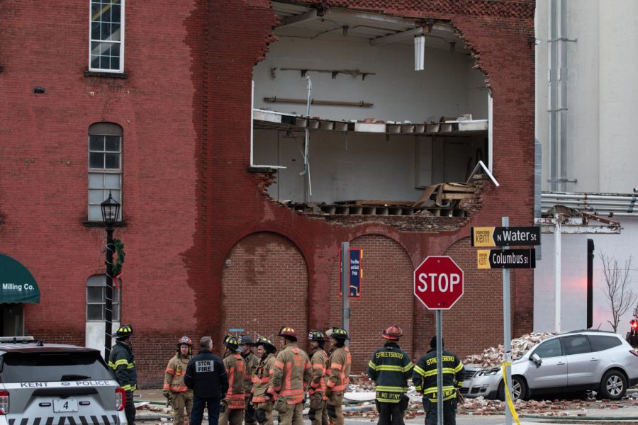 Firemen congregate outside of the Star of the West Mill beneath a gaping hole in the buildings front wall, caused by an explosion during the fire.