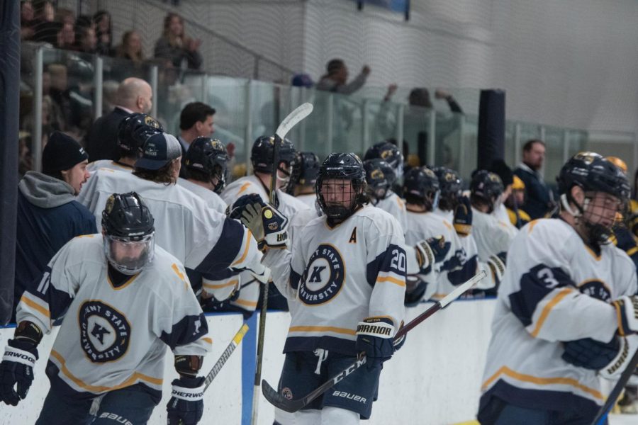 Kent State hockey team members Mitch Gillespie (left), Zachary Barnes (center) and Nick Kreston (right) high-five their teammates on the bench alongside the rest of the players on the ice after a succesful goal during the home game against West Virginia University on Jan. 28th, 2023. 