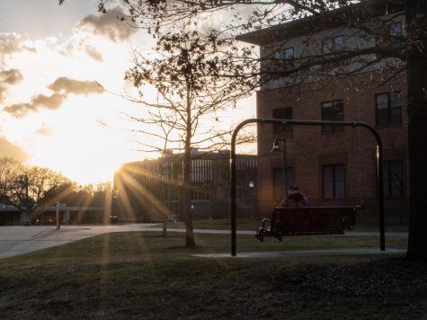A Kent State student sits on the swing bench outside the Honors Collage and enjoys the sunset on Feb. 23, 2023.