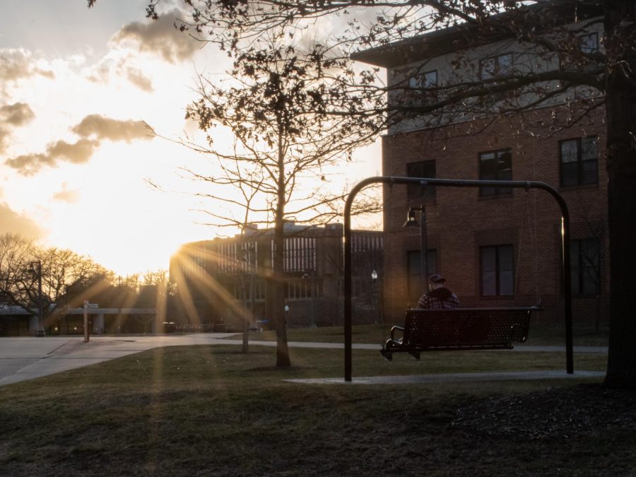 A Kent State student sits on the swing bench outside the Honors College and enjoys the sunset Feb. 23, 2023.