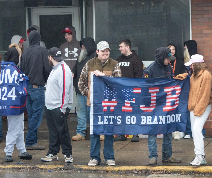 East Palestine residents and visitors stand on North Market Street on Feb. 22, holding a flag that reads #FJB Lets Go Brandon. Attendees were waiting outside for former president Donald Trumps visit since 9 a.m.