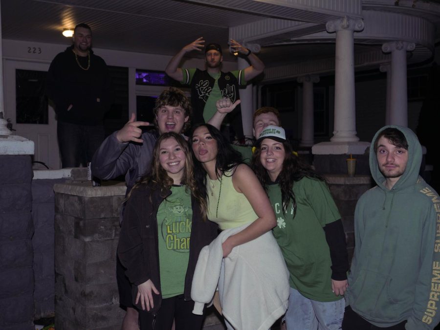 Emma Chelling (center) and Grace King (center left) wait outside the Delta Tau Delta house with friends and partygoers for Kents Fake Pattys Day Celebration Mar. 11.