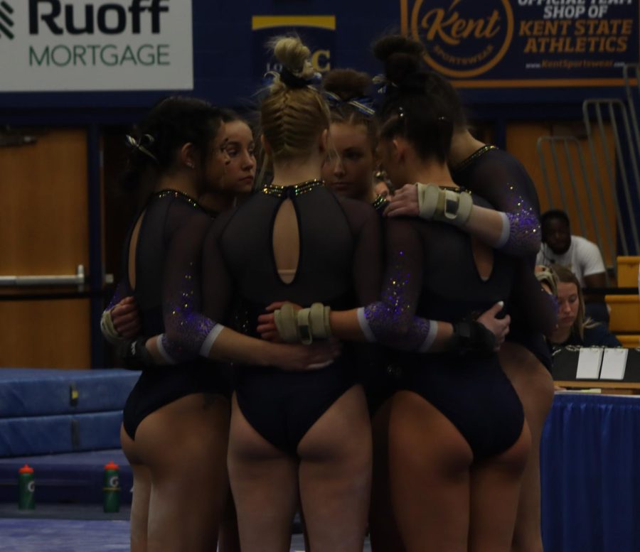 the gymnastics team doing a group huddle before the final event for the Kent vs Michigan meet on 3/12/23