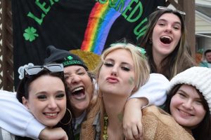 Kent State University students pose in front of a backdrop on the deck of a fraternity during a Fake Paddys party March 11, 2023.