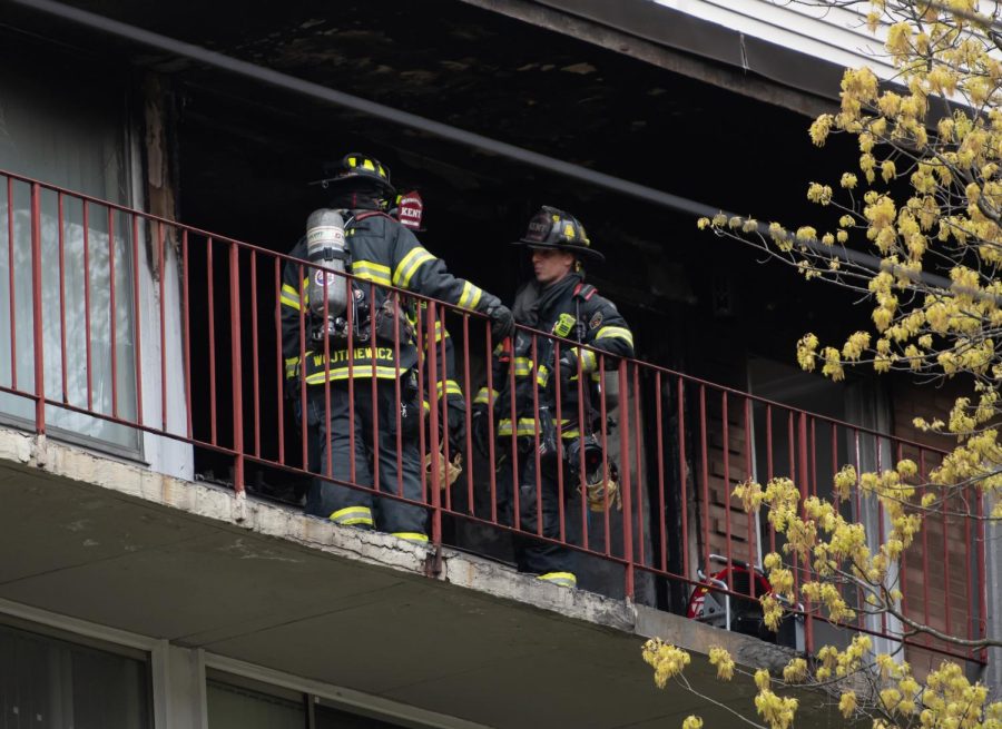 Kent firefighters stand outside of the burned apartment at University Inn on South Water Street after putting out the fire on May 2, 2023.