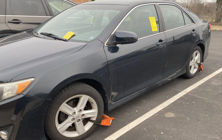 A car parked in the R-3 lot near Taylor Hall has two boots and is plastered with tickets on February 14, 2023. According to Kent States Parking and Transit Services, a car that has been issued nine or more tickets is at risk of booting or towing.