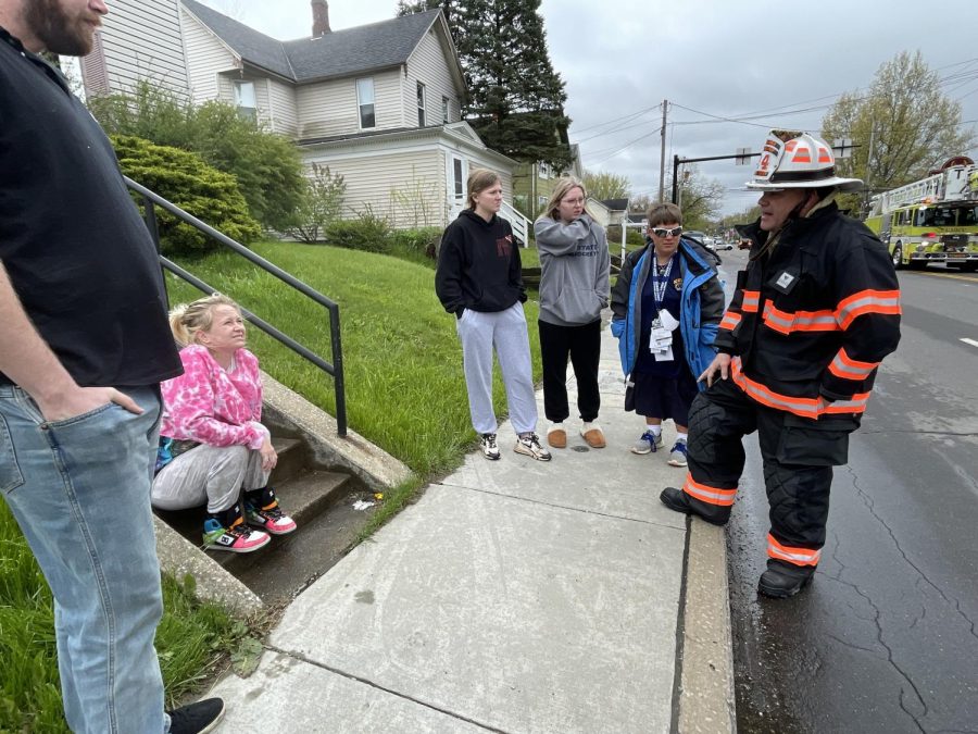 A Ravenna fire chief tells Hannah Fuller, at left sitting on the step, that a warming center is open at the Trinity Lutheran Church down the street. Fuller lives in a seventh-floor apartment at University Inn on South Water Street in Kent and had to evacuate during a fire this morning in an apartment three doors down from hers. At far left is Colin Gray, who lives with her in the apartment. They were both worried about the status of their two cats.