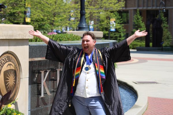 Gavin Aitken celebrates his graduation while standing in front of the Kent State University fountain sign in May 2023. He now works as a graduate teaching assistant the University of Tennessees Jones Center for Leadership and Service.