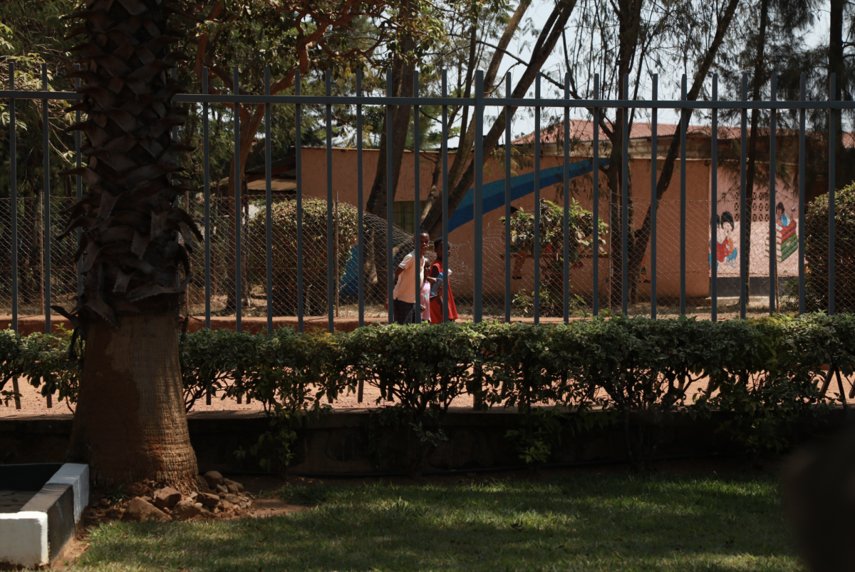 Outside the Nyamata Genocide Memorial, kids laugh in the distance and walk past the church on their way to school, looking in through the fence.