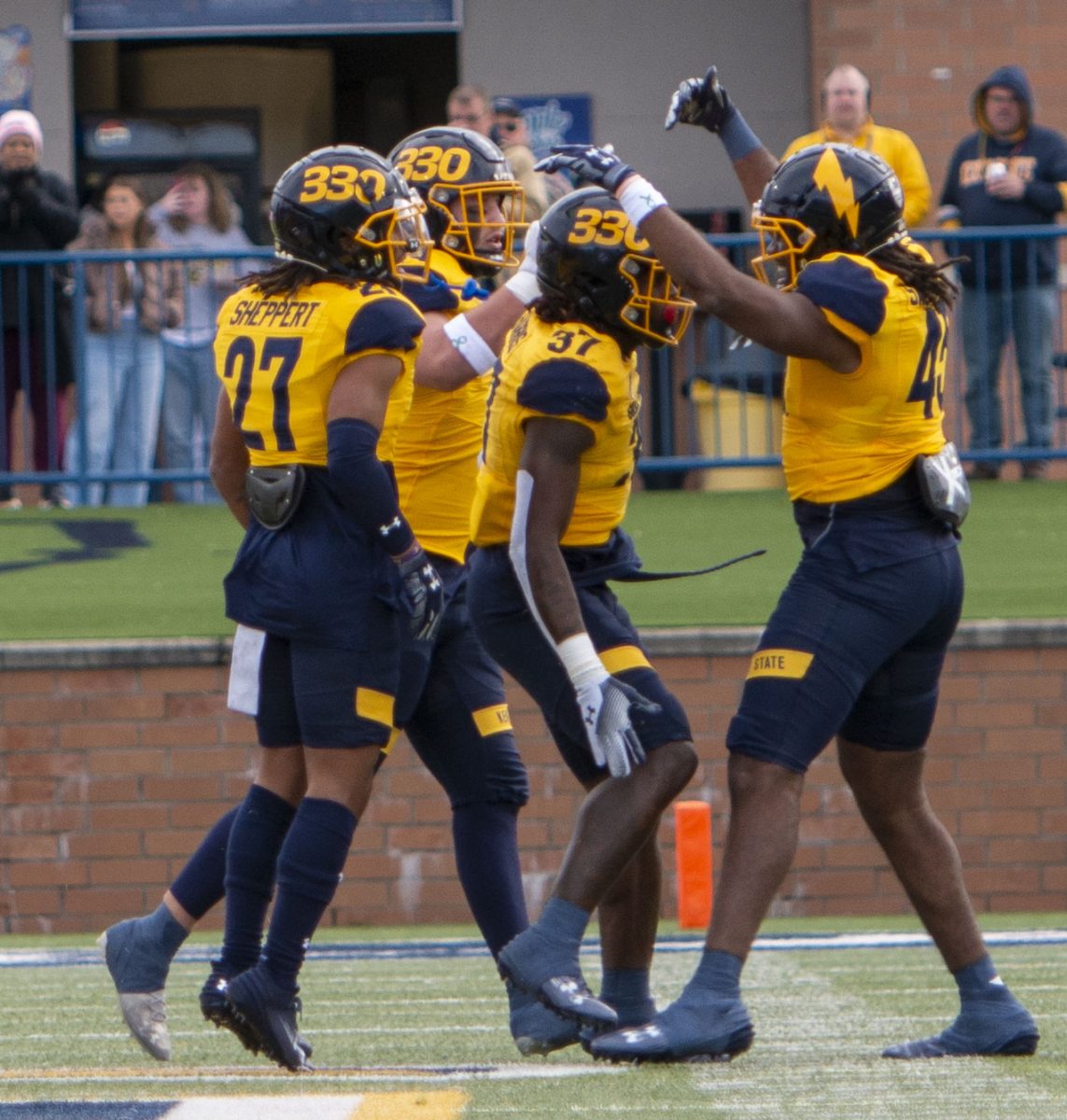 Senior linebacker Khali Saunders (45), graduate student safety Bryce Sheppert and sophomore defensive lineman Oliver Billotte celebrate around fellow senior linebacker C.J. Harris (37) after a Harris tackle-for-loss in the first quarter of the Kent State vs. Buffalo football game on Oct. 21, 2023.  