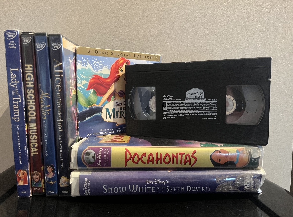 A collection of VHS tapes, DVDs and CDs of classic childhood Disney movies. 