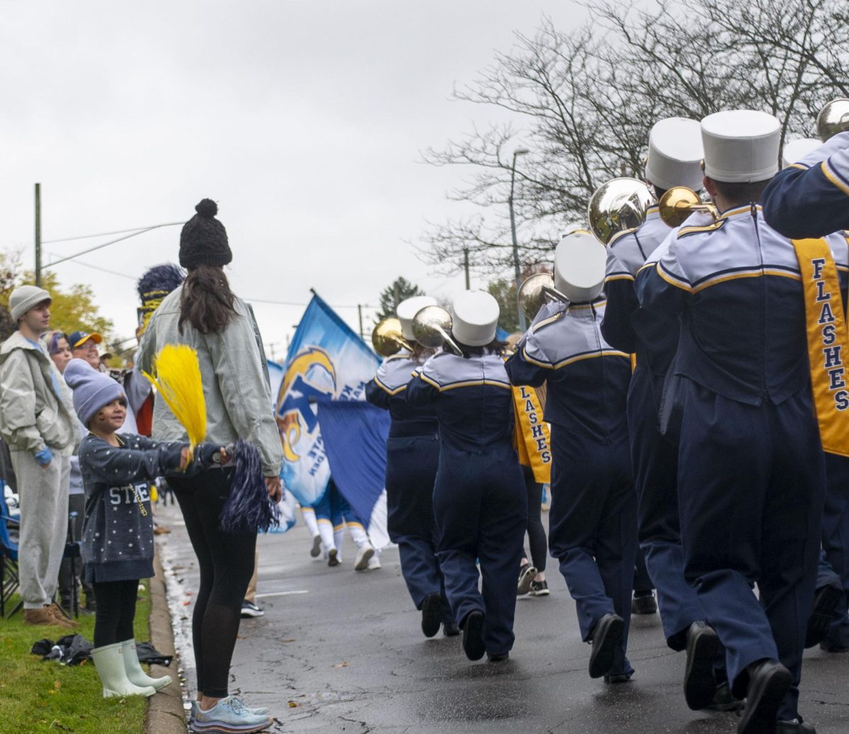 A young flashes fan waves her pom-poms with the Kent State Marching Golden Flashes as they pass by playing the Fight Song during the Homecoming Parade on Oct. 21, 2023.