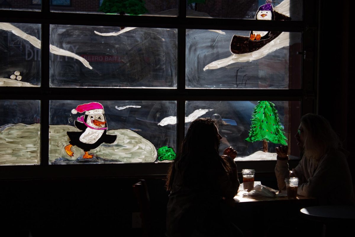 Costumers enjoy coffee at Tree City in front of their decorated windows. 