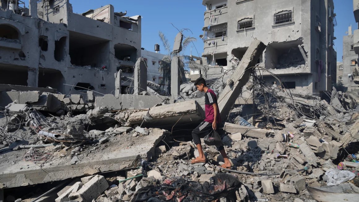 Palestinians+stand+by+buildings+destroyed+in+Israeli+airstrikes+in+Deir+al-Balah%2C+Saturday%2C+Oct.+14%2C+2023.+Amnestys+report+focused+on+two+strikes+in+this+neighborhood.