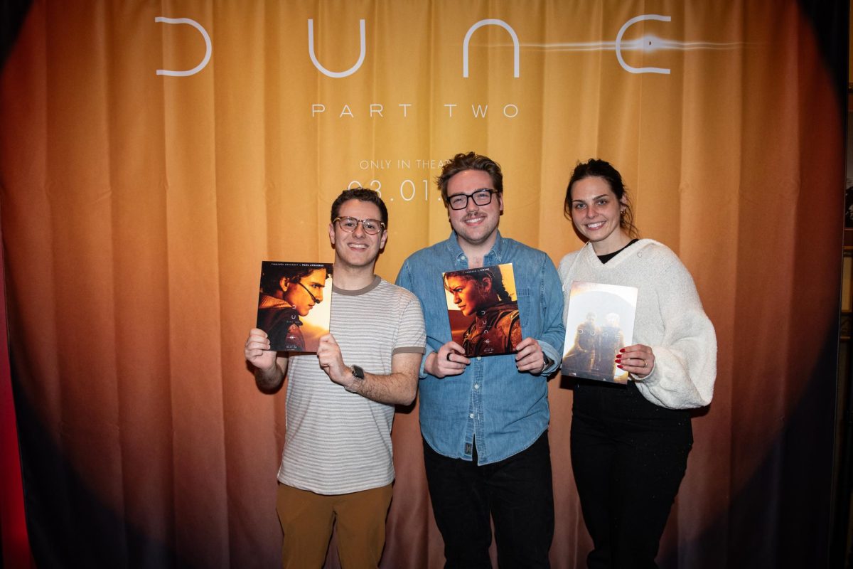 Brandon Rock, Dan Chastant and Kelly Geringer stand for a picture in front of the Dune Part Two backdrop hung outside the theater the movies premiere was shown at Cinemark Valley View and XD in Cleveland on Feb. 27, 2024.