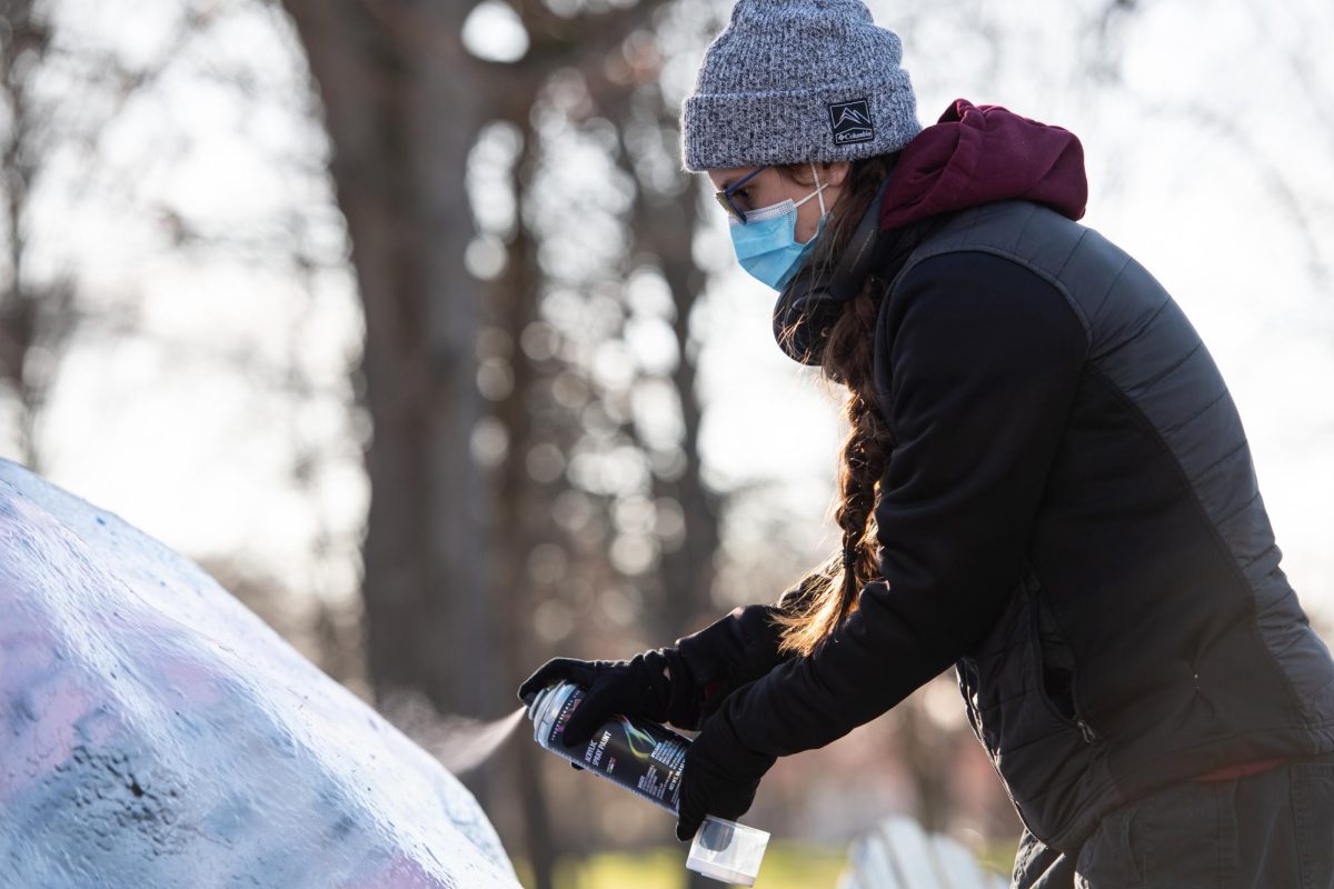 Kent student Harley Hill paints the rock during the KSURGE Candlelight Vigil on March 21, 2024. The vigil was held in memory of Nex Benedict, who died in February. 