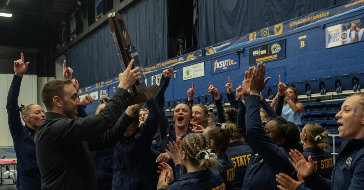 Associate Head Coach Craig Ballard presents the Kent State Gymnastics team with the regular season championship trophy. Kent State shares the 2024 championship with Ball State, which is their second championship in three years, having shared it in 2022 with Central Michigan.