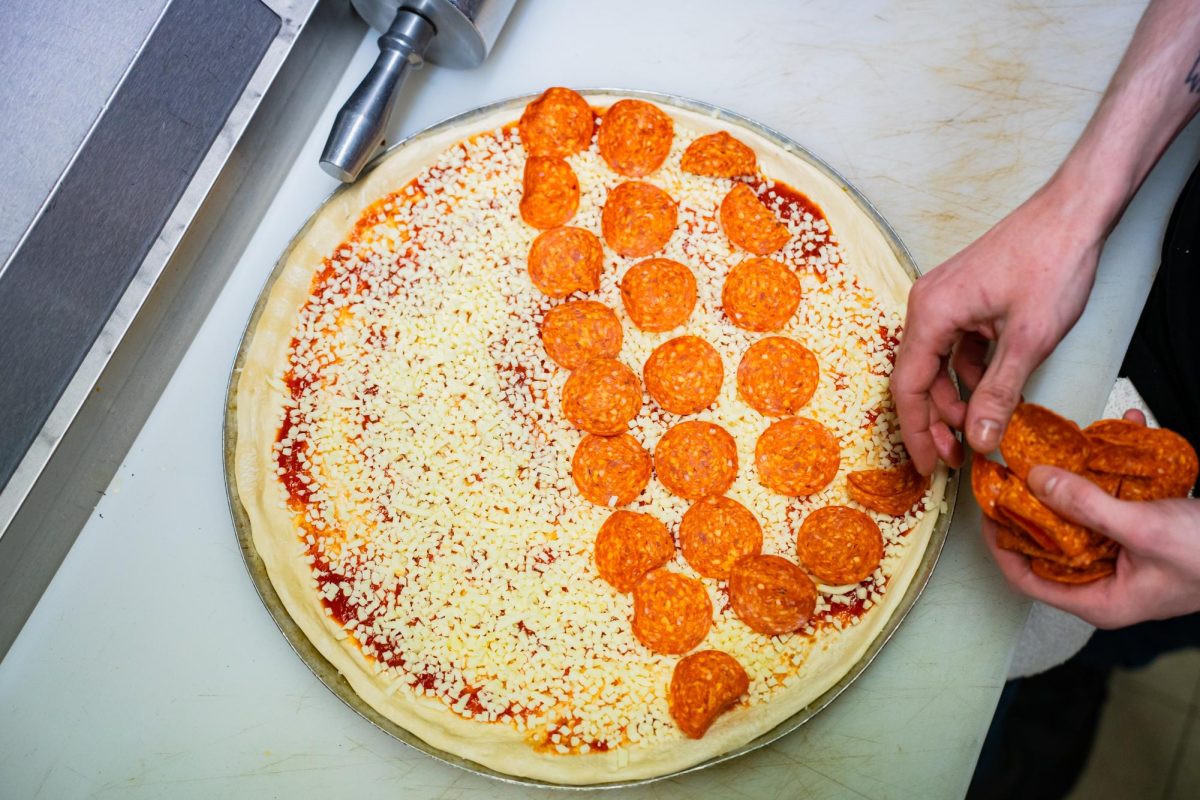A employee of Guys Pizza Co. prepares the final touches of an order.