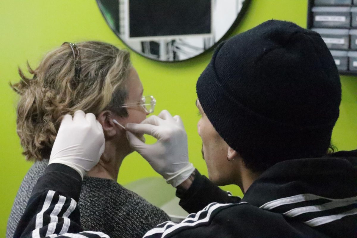 Aaron Bohn cleans Gail Cowley ear for her piercing at Defiance Tattoos on March 21, 2024. 