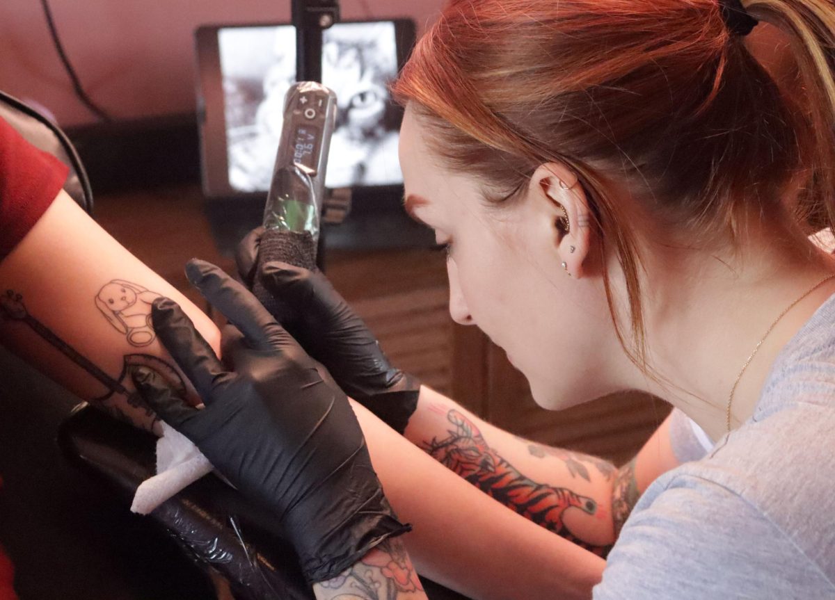 Tattoo artist at  Rotten Peaches Studios co-founder Erin Haineys works on Lillis tattoo in the likeness of her cat in a locket on March 21, 2024. Rotten Peaches Studio is located 1480 S Water St.
