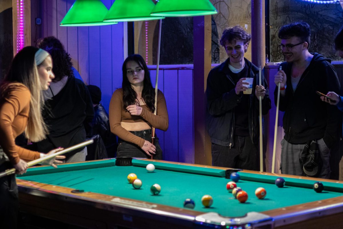 Jude Miller, Theo Beukemann, Olivia Woods, and Drew Berkshire play pool together before singing karaoke at the Burnt Pickle on March 20, 2024.