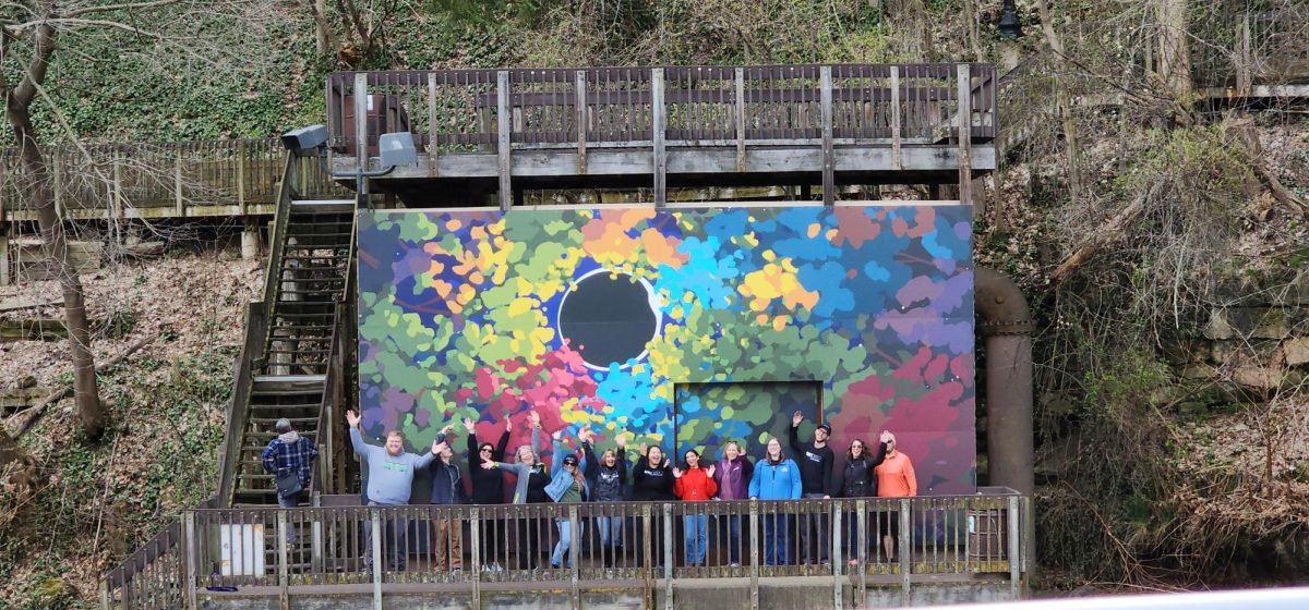 Locals pose in front of new eclipse-themed mural, unveiled April 6.