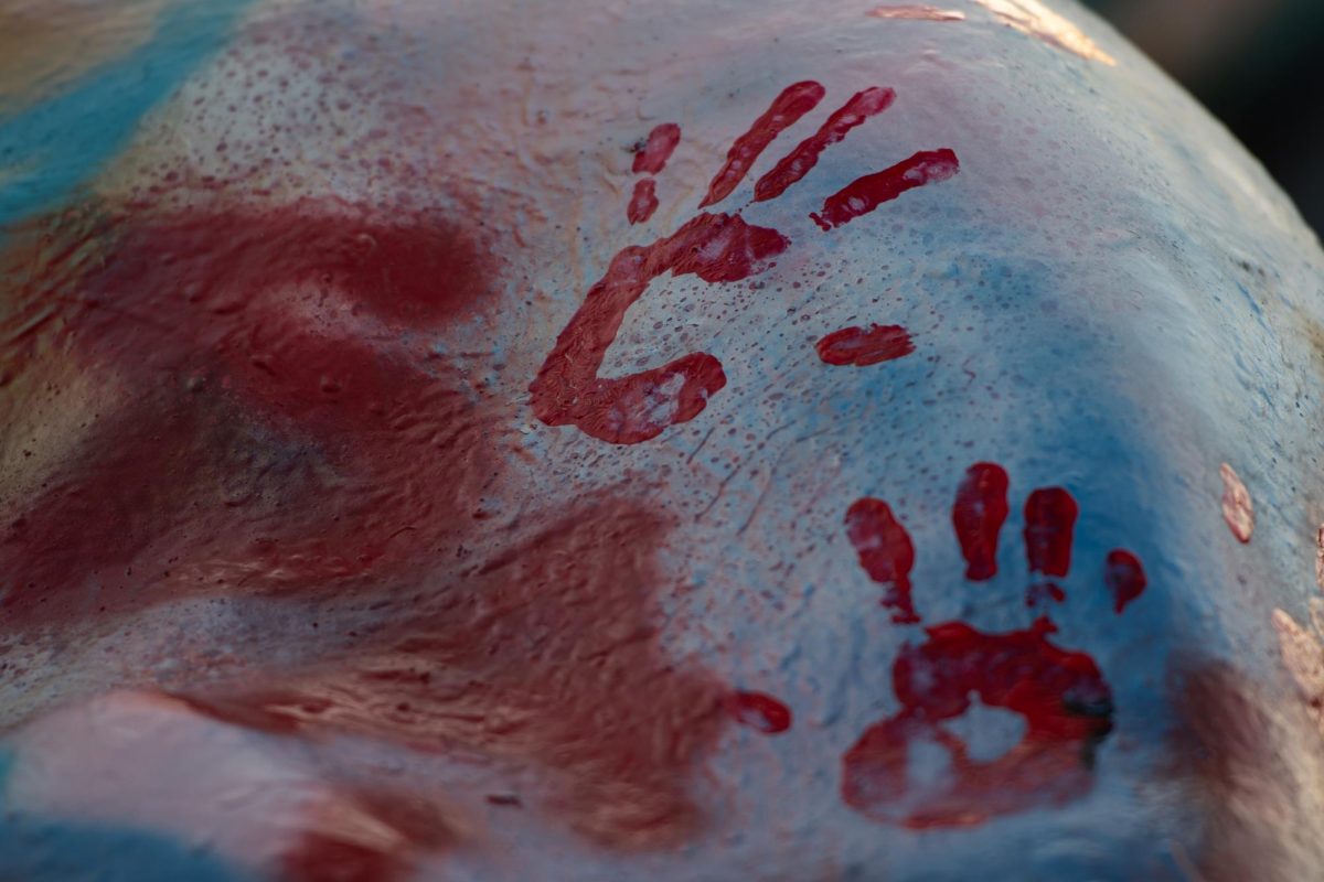 Using red paint, participants of the protest on April 15, 2024, leave handprints behind on the Rock after painting it.