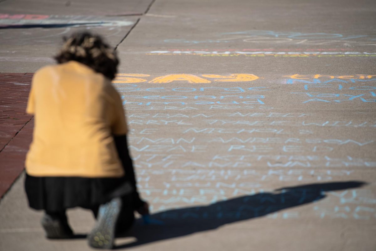 Sunshine, a member of Serve The People Akron, uses chalk to write down the names of people of color who also their lives due to hate crimes and police brutality during the protest April 15, 2024.